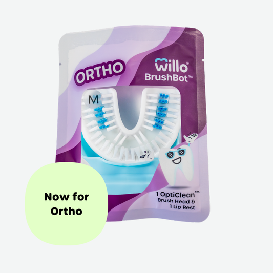 Sealed pouch packaging for the Willo BrushBot Ortho brush head with a clear window showing a white and blue size M mouthpiece, featuring a light green badge that reads "Now for Ortho".