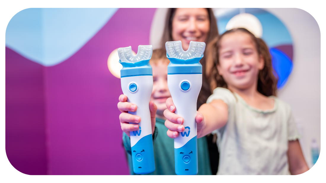 Two kids holding Willo kids automatic brushing toothbrush in a bright bathroom