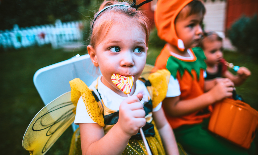 Girl in a Halloween costume eating a lollipop