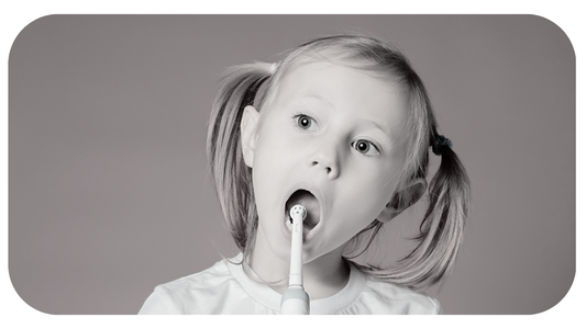 girl holding an electric toothbrush but missing her teeth