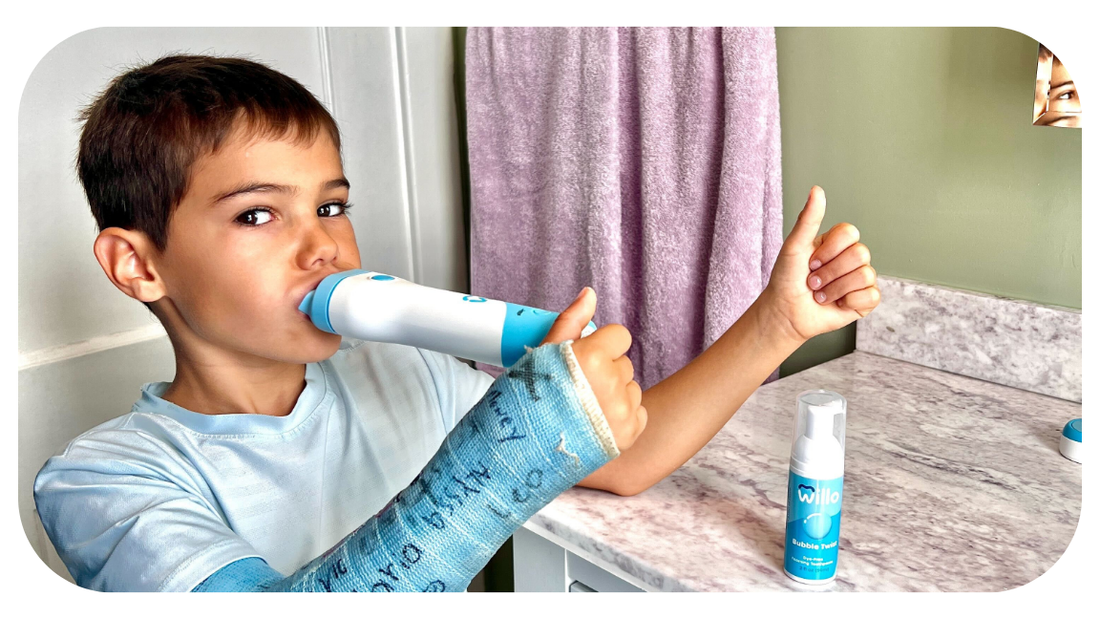 Boy with a broken arm using Willo kids automatic brushing toothbrush in a bright bathroom