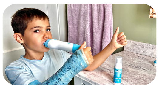 Boy with a broken arm using Willo kids automatic brushing toothbrush in a bright bathroom