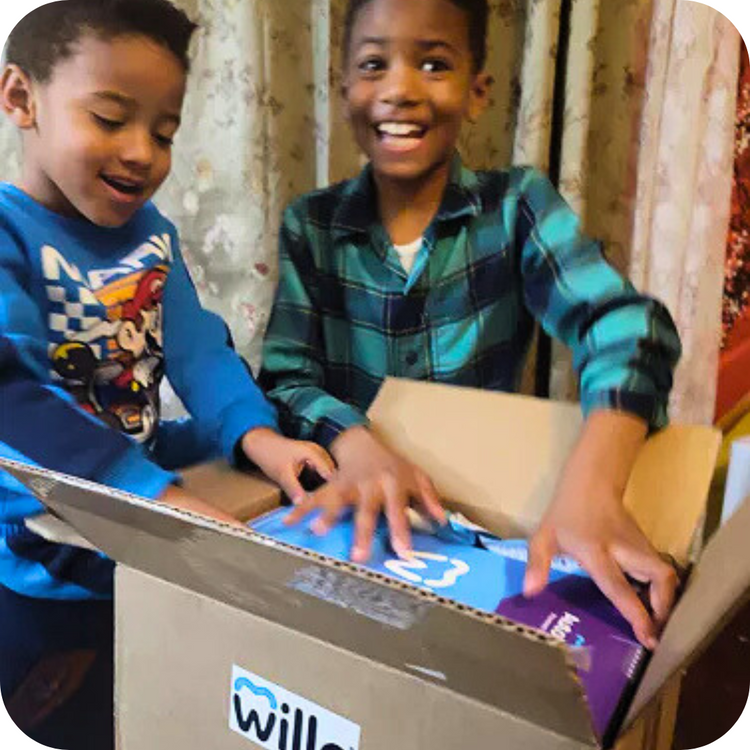 Sibling user-generated content (UGC) lifestyle photo capturing two young boys laughing happily while unboxing their Willo smart dental care shipping package at home.