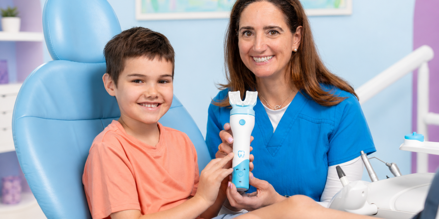 Dentist and young patient smiling while holding a Willo automatic toothbrush in a dental clinic.