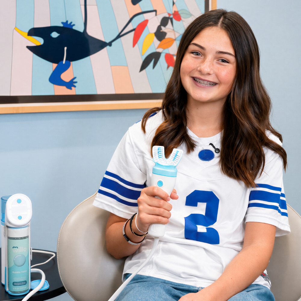 Teenage girl with braces holding a willo ortho toothbrush in an orthodontist office